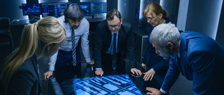 Government intelligence officials standing around table in monitoring room