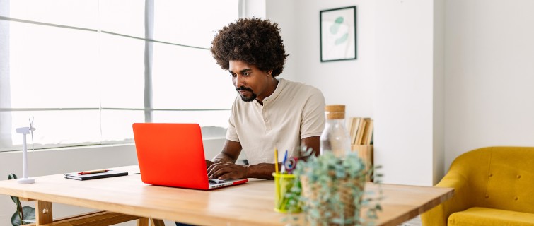 Young Black person working on a laptop at home office.