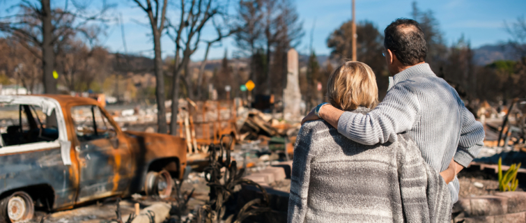 Couple looks out at wreckage from natural disaster.