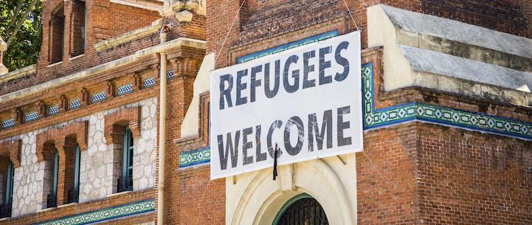 Banner saying "Refugees Welcome" hangs above the door of a church