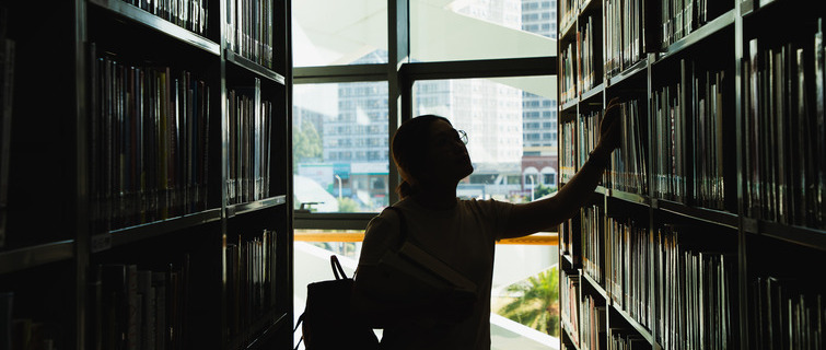 Student in silhouette looking at the books