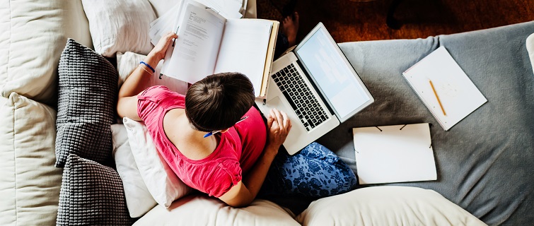 Woman sitting on couch working on laptop