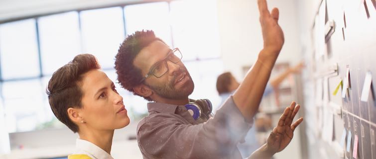 Woman and man collaborate at whiteboard