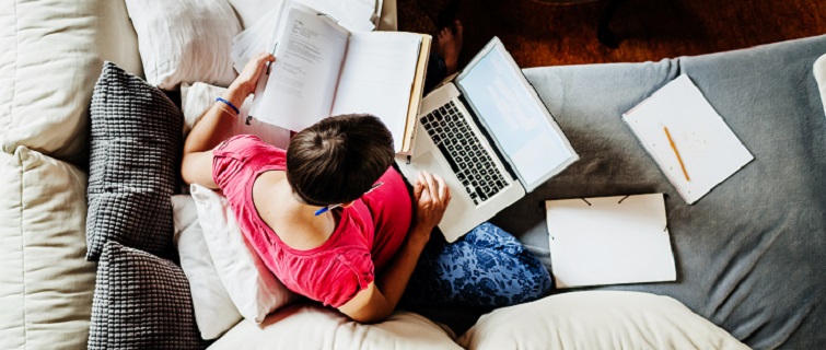 Woman sitting on couch working on laptop