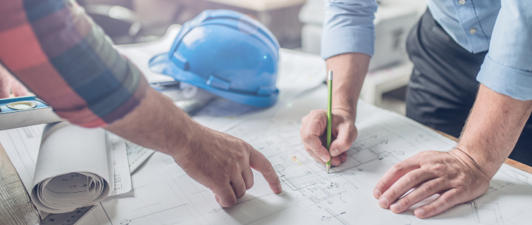 Hands of an architect and an engineer pointing at an architectural plan.