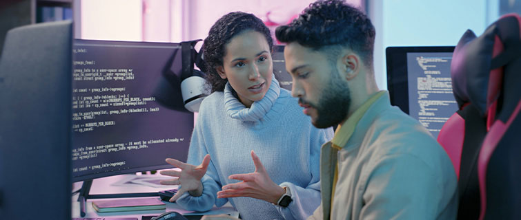 Woman talking to man in front of computer