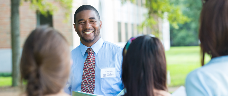 College campus tour guide talking with prospective students outdoors.