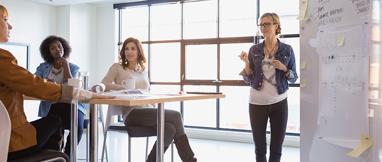 woman in front of whiteboard talking to group