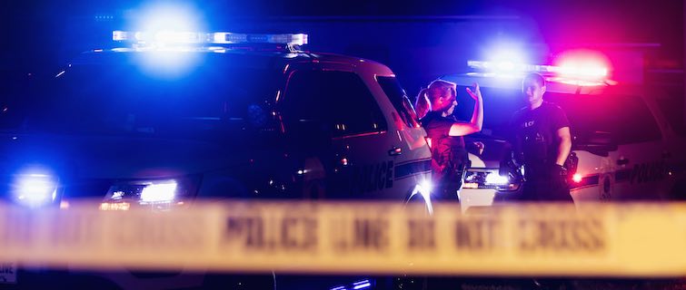 two police officers behind crime scene tape