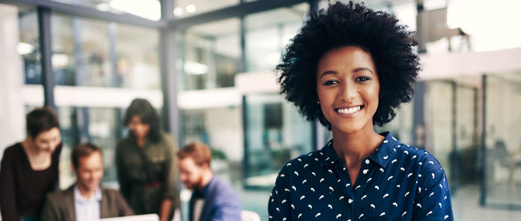 Young woman standing in a modern office with her colleagues