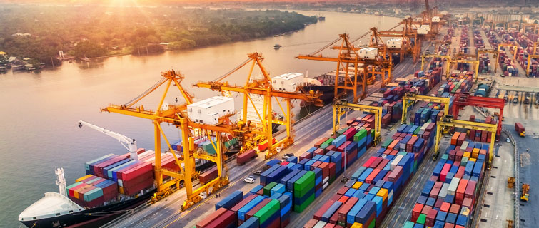 Aerial view of busy port with shipping containers in foreground.