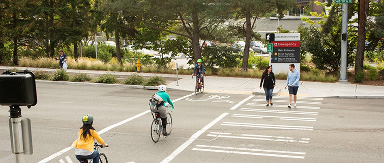 people walking and biking across a city street crosswalk
