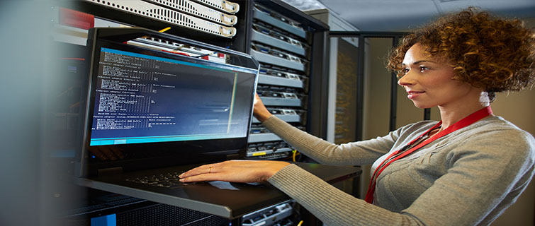 Woman standing next to a laptop and computer server