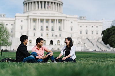 Three students on lawn outside of US capitol